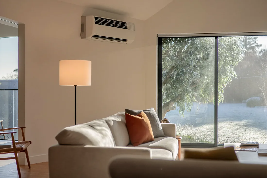 A warm, energy-efficient Canberra living room on a frosty winter morning, where a home's energy efficiency rating shapes heating running costs.