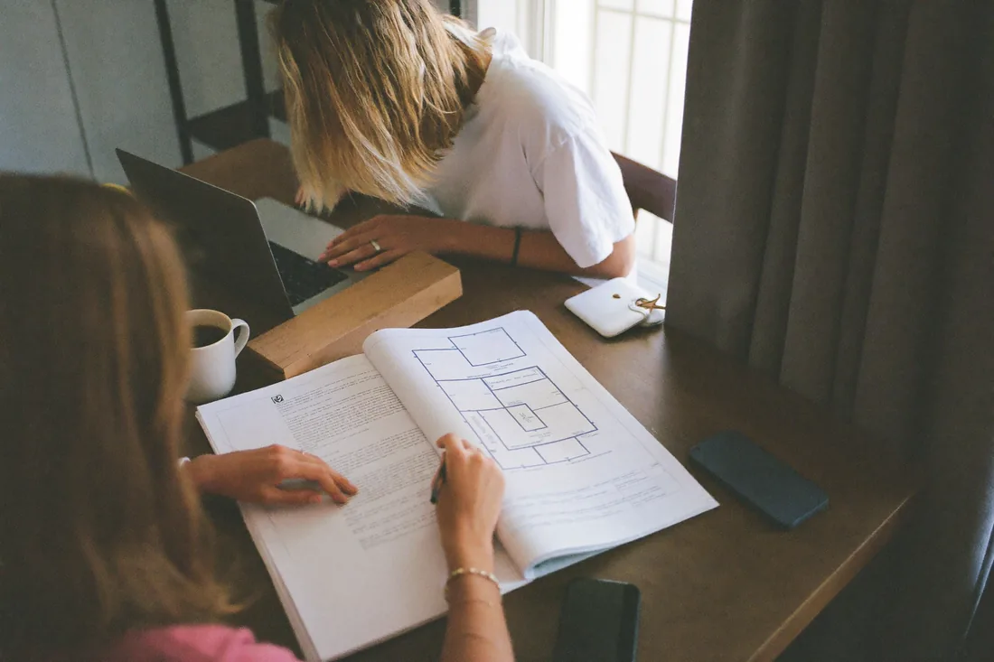 Australian first home buyers reviewing a thick off-the-plan contract and floor plan at their kitchen table before signing.
