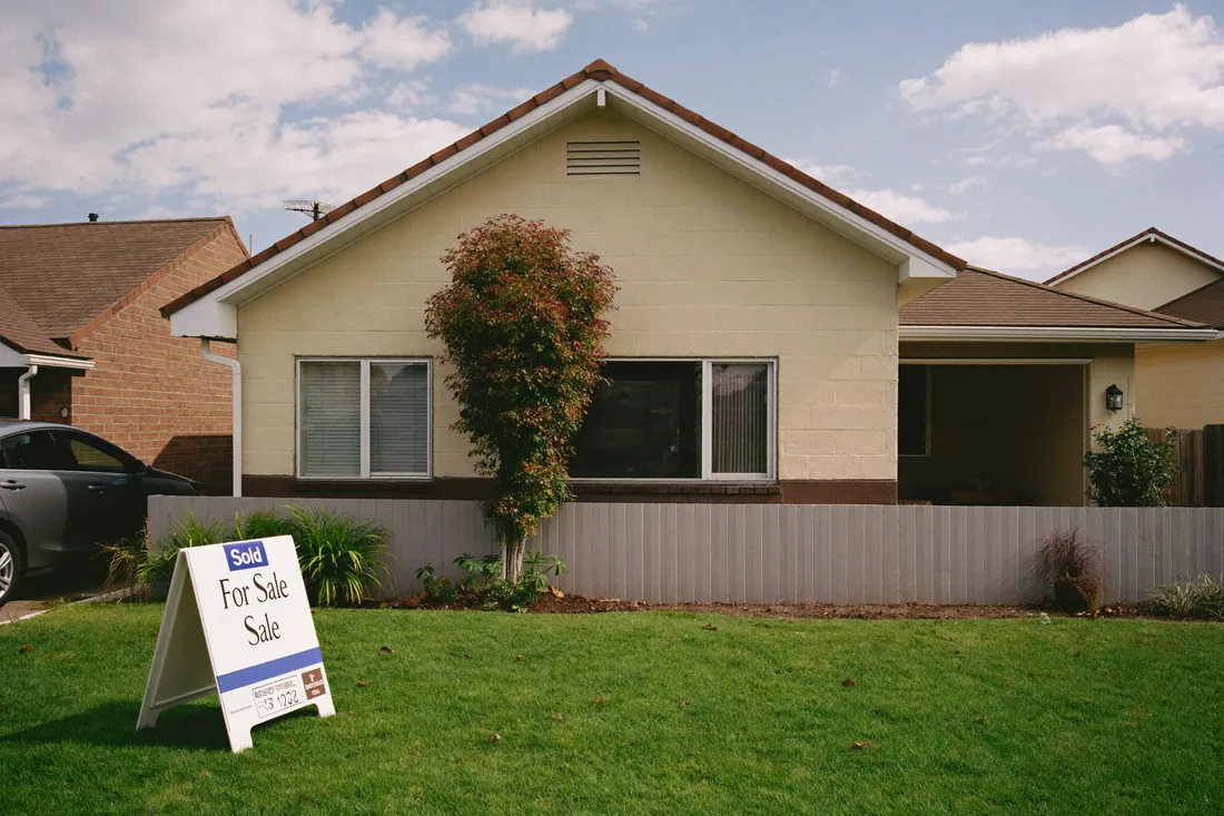 A suburban Australian house with a Sold sign out the front, representing the sale of an investment property that triggers capital gains tax.