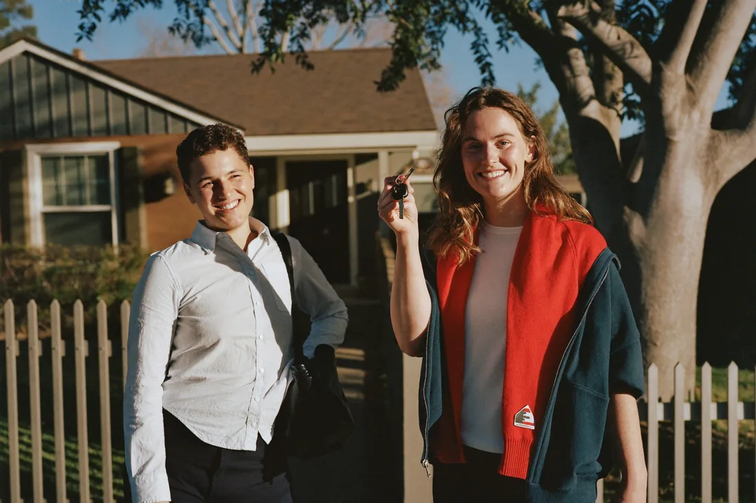First-home buyers standing outside their newly purchased suburban Australian home.