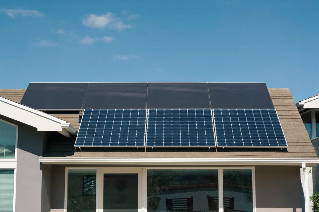 An established Australian suburban house with a tidy garden and rooftop solar panels, representing the ongoing running costs of home ownership.