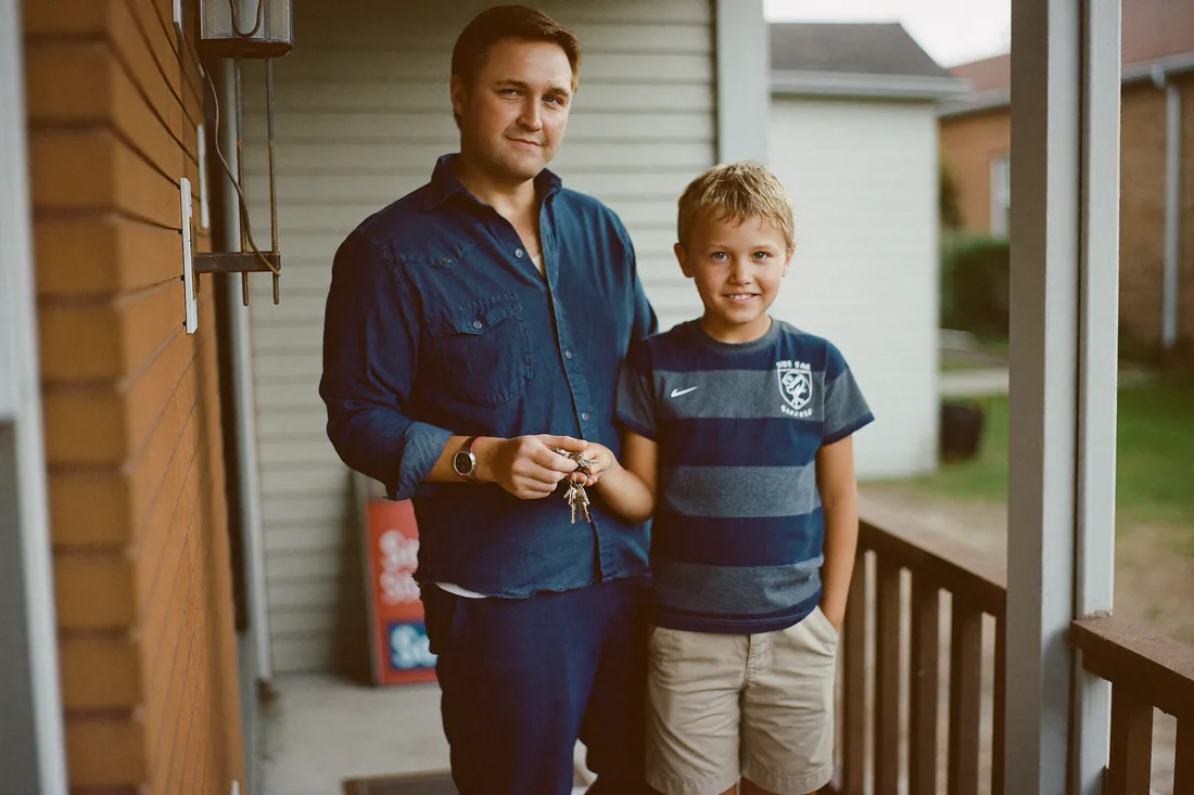 Single parent and child on the front step of their new Australian home holding the keys after settlement.