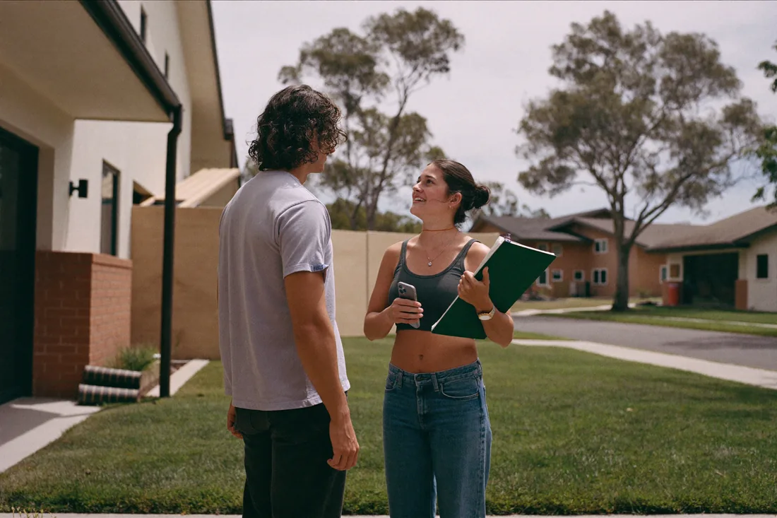A young Australian couple looking at a newly built suburban house, the kind of new build most state first home owner grants are restricted to.