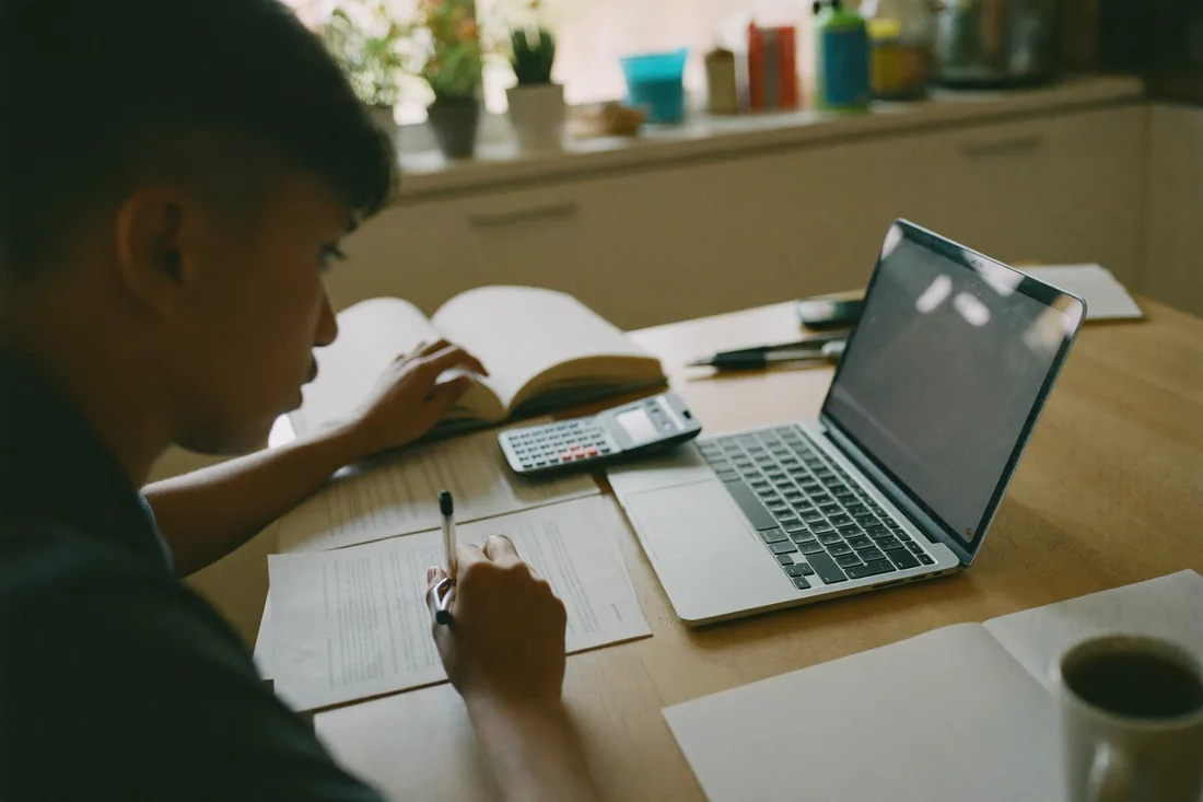 A first home buyer working through grant and stamp-duty paperwork at home with a calculator and laptop before lodging an application.