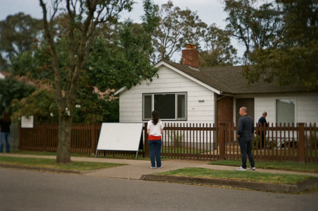 Prospective first home buyers standing outside a suburban Australian house on inspection day.