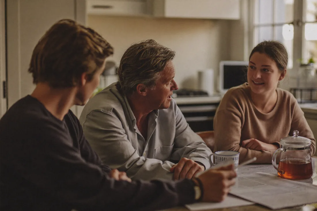 Australian parents and their two adult children talking together at a kitchen table about going guarantor on a home loan.