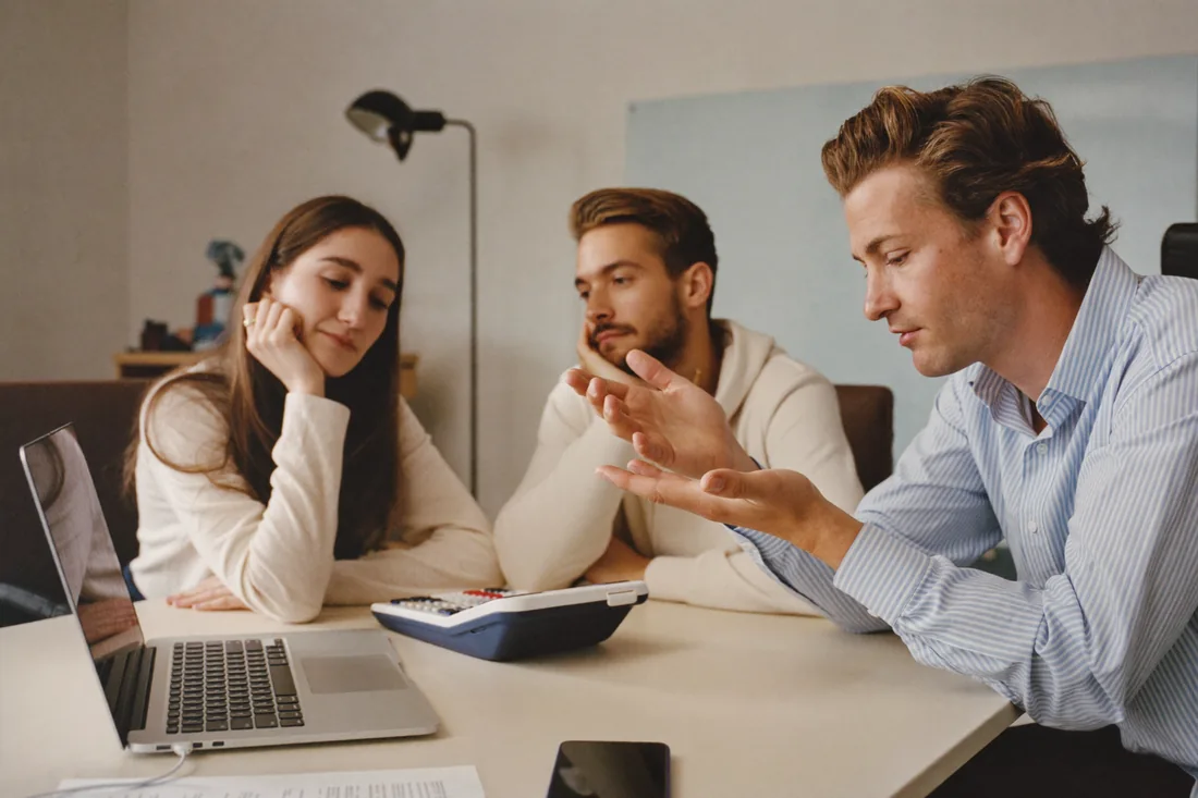 A mortgage broker explaining to a young couple how their HECS repayment affects their home loan borrowing power.