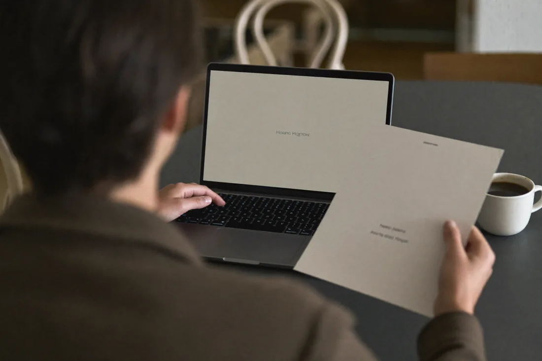 A person at a kitchen table beside a laptop and coffee working out their home contents insurance cover.