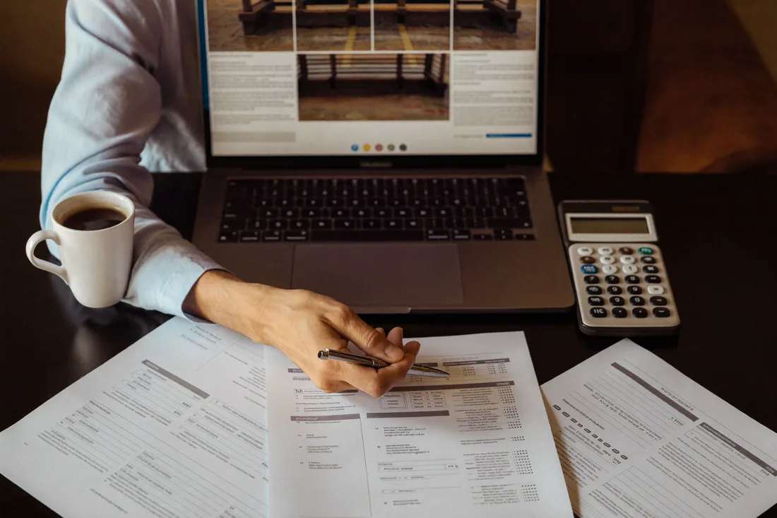 An Australian property investor reviewing an annual land tax assessment notice and calculating the cost on a laptop at home.