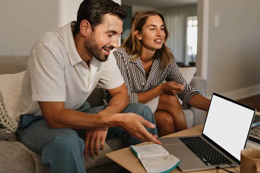 A couple at home working out their refinancing savings on a laptop in a relaxed suburban living room.