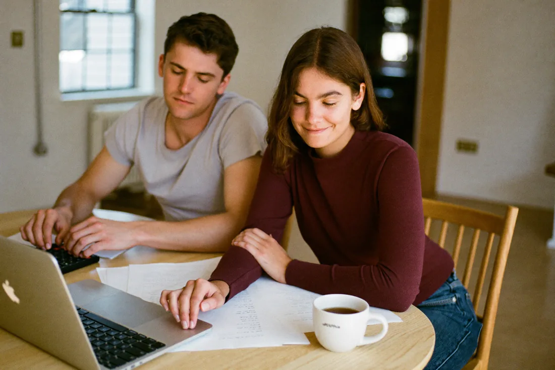 A first home buyer couple working out their stamp duty costs on a laptop at their kitchen table.