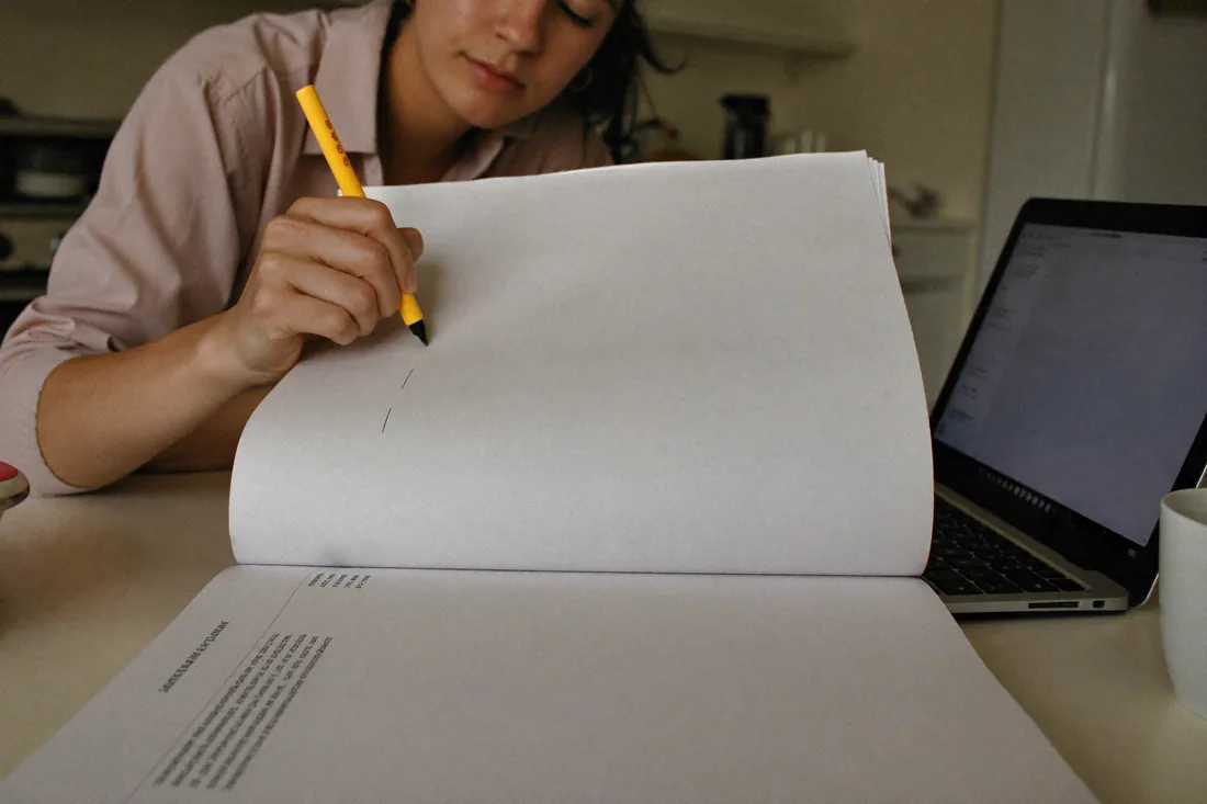 An everyday Australian first home buyer works through a printed strata report with a highlighter at a kitchen table.