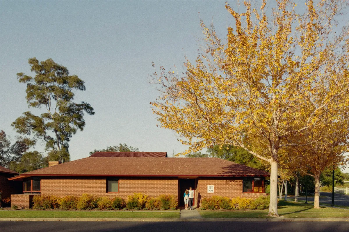 A mid century brick home on a leafy Canberra street in autumn